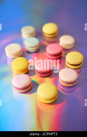 Macaron à gâteau français. Ensemble de bonbons mignons sur fond coloré arc-en-ciel. Biscuits aux amandes, couleurs pastel, vue du dessus Banque D'Images