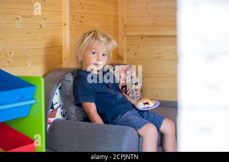 Adorable petit garçon, jouant dans une maison de poupée en bois dans le jardin, regardant dehors Banque D'Images