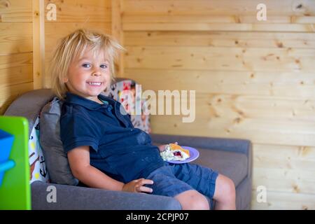 Adorable petit garçon, jouant dans une maison de poupée en bois dans le jardin, regardant dehors Banque D'Images