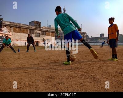 DISTRICT KATNI, INDE - 02 DÉCEMBRE 2019 : les garçons de la ville indienne jouent ensemble au football sur un terrain de jeu de forester autour d'un magnifique champ de ciel. Banque D'Images