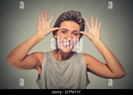 Gros plan portrait drôle, jeune, puérile, femme impolie et stupide qui colle la langue à votre geste de caméra, isolée sur fond gris. Émotion humaine faci Banque D'Images