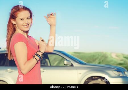 Heureuse voiture souriante femme souriante montrant de nouvelles clés de voiture et en voiture le jour d'été ensoleillé Banque D'Images