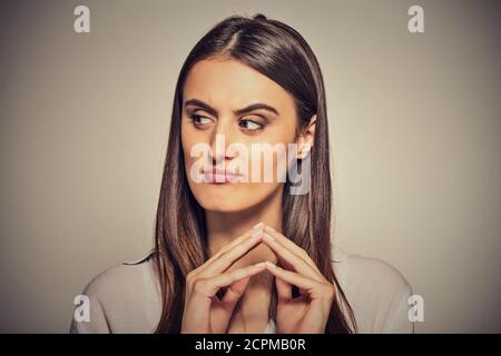 Closeup portrait of sneaky, Sly, intrigant jeune femme traçant quelque chose d'isolé sur fond gris. Des émotions négatives, les expressions du visage, frais Banque D'Images