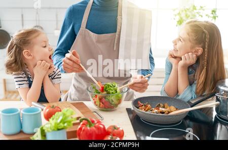 Une alimentation saine à la maison. Bonne famille dans la cuisine. Père et enfants les filles préparent un bon repas. Banque D'Images