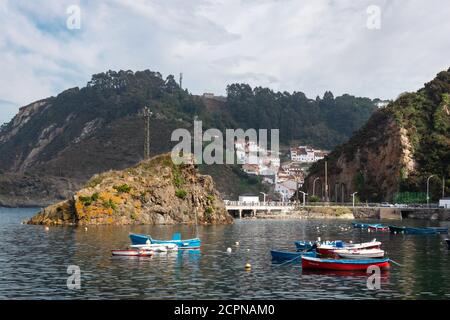 Bateaux de pêche à la mer. Eau calme au port naturel entre les falaises. Petit village de pêcheurs avec maisons blanches construites sur la colline. Cudillero, Astur Banque D'Images