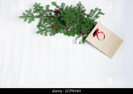 Des branches d'épinette avec des jouets du nouvel an et un sac-cadeau se trouvent sur un fond blanc. Banque D'Images