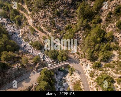 Route sinueuse et pont en pierre étroit passant par un dégagé Ruisseau de montagne dans les montagnes de l'Asco de Corse Banque D'Images