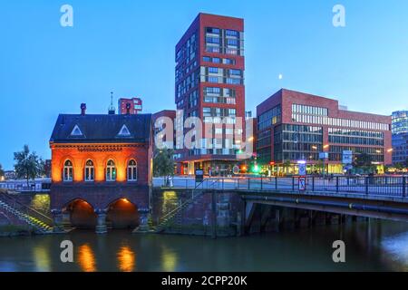 Scène nocturne dans le quartier des entrepôts (Speicherstadt) de Hambourg, en Allemagne, avec Fleetschlosschen, l'un des premiers bâtiments du quartier guar Banque D'Images