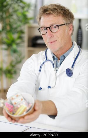 portrait d'un médecin expérimenté offrant un bouquet de pilules Banque D'Images