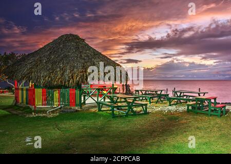 Coucher de soleil au 3 Dives point à Negril, Jamaïque. Une hutte en bois, aux couleurs jamaïcaines, se dresse au sommet d'une falaise très populaire auprès des cavaliers. Banque D'Images