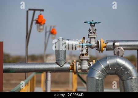 Raffinerie de pétrole dans le désert. Armature de soupape et tuyaux sur fond gris ciel. Mise au point sur le premier plan. Banque D'Images