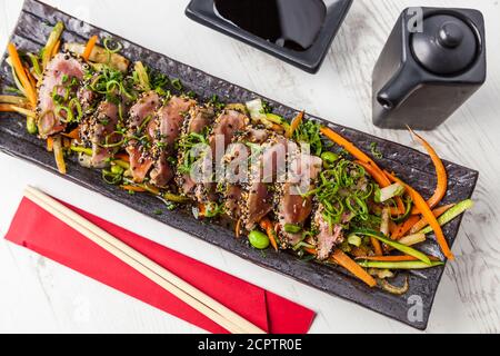 Cuisine japonaise. Tatataki de thon. Thon poêlé aux graines de sésame et sauce soja, wasabi, lime. Banque D'Images