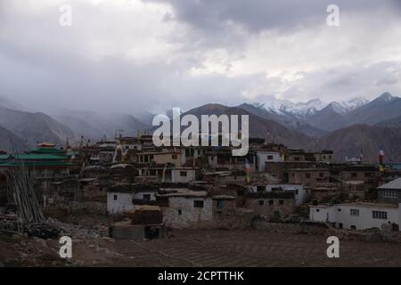 Les nuages se rassemblent au-dessus du village de Nako à Kinnaur un après-midi alors qu'une porte rouge d'une maison est maintenue fermée. Vue panoramique sur les maisons du village. Porte rouge traditionnelle. Banque D'Images