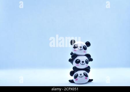 Petites figurines en porcelaine empilées de panda isolées sur fond noir Banque D'Images