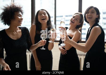 Les jolies dames surjoyées dans des robes noires appréciant le temps de la fête. Banque D'Images