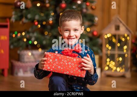 Noël fabuleux, petit garçon tenant une grande boîte rouge avec un cadeau de Santa. Banque D'Images