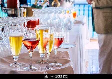 Gros plan sur des verres avec des boissons fraîches et savoureuses avec de l'alcool et pas sur une table pendant la restauration de fête - restaurant et les gens dans défocused Banque D'Images