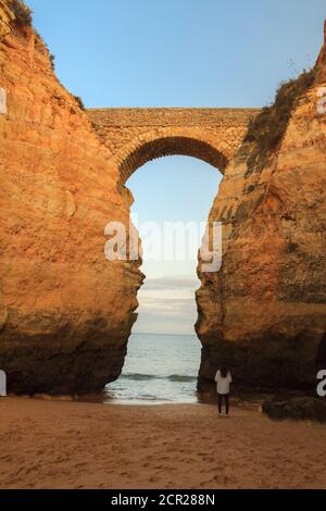 Plage Praia dos Estudantes au coucher du soleil avec pont d'arche à Lagos, Algarve, Portugal Banque D'Images