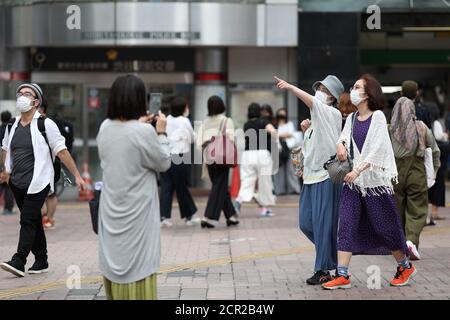 Les gens portant des masques faciaux sont vus marcher de la gare à Shibuya Crossing.Shibuya Crossing n'est pas aussi surpeuplé qu'il était avant le nouveau coronavirus cependant la vie continue à l'intersection la plus célèbre de Tokyo que le port des masques faciaux devient une nouvelle norme. Banque D'Images