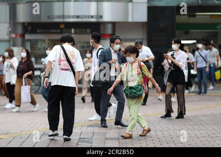 Les gens portant des masques faciaux sont vus marcher de la gare à Shibuya Crossing.Shibuya Crossing n'est pas aussi surpeuplé qu'il était avant le nouveau coronavirus cependant la vie continue à l'intersection la plus célèbre de Tokyo que le port des masques faciaux devient une nouvelle norme. Banque D'Images