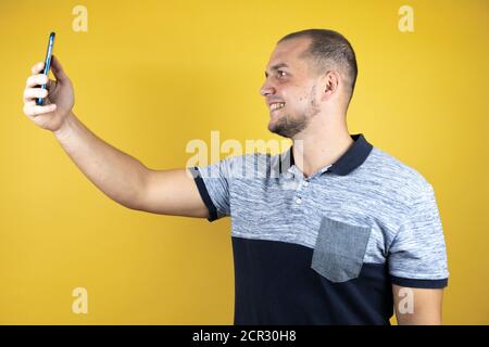 Homme russe debout sur fond jaune insolé prenant lui-même un selfie. Banque D'Images