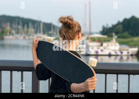 Une fille se tient avec une longue planche sur un pont dans un port de voile Banque D'Images