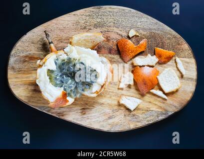 granadilla douce ou Passiflora ligularis sur des planches à découper en bois sur fond sombre. Délicieux fruits exotiques tropicaux. Vue rapprochée. Banque D'Images