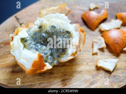 granadilla douce ou Passiflora ligularis sur des planches à découper en bois sur fond sombre. Délicieux fruits exotiques tropicaux. Vue rapprochée. Banque D'Images