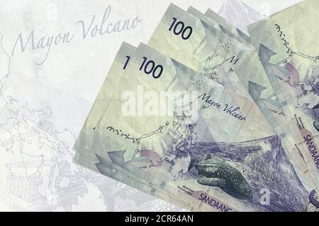 100 les billets de piso philippins sont empilés sur le fond d'un grand billet de banque semi-transparent. Présentation abstraite de la monnaie nationale. Concept d'entreprise Banque D'Images