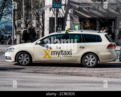 Hambourg, Allemagne - 20 mars 2020 : vue latérale de l'application jaune Volkswagen Mytaxi dans le centre de Hambourg avec des piétons qui marchent en arrière-plan Banque D'Images