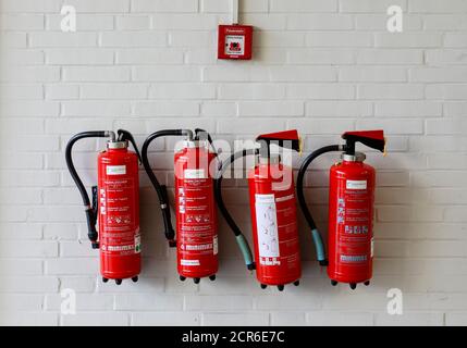 Hanovre, Basse-Saxe, Allemagne - quatre extincteurs rouges sur un mur sous une alarme incendie à la Messe de Hanovre. Banque D'Images