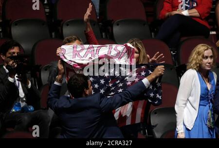 Supporters of Republican U.S. presidential nominee Donald Trump obscure a protestor from the activist group Code Pink who is holding an anti-racism and anti-hate banner as she interrupts the proceedings during the second day of the Republican National Convention in Cleveland, Ohio, U.S. July 19, 2016. REUTERS/Mike Segar