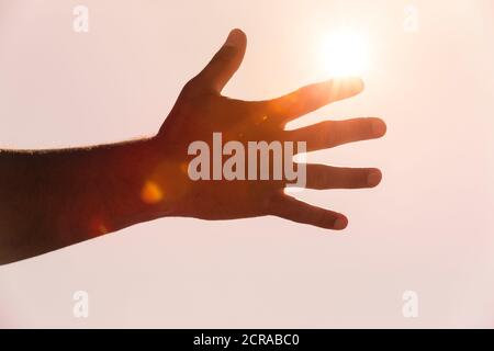 Main de l'homme dans le dos lumineux avec des rayons de soleil Banque D'Images