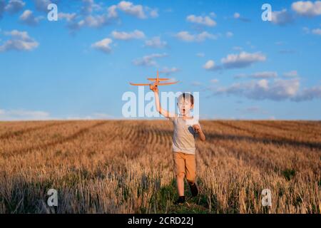 Enfant heureux courant avec avion jouet sur fond de ciel concept de famille heureux. Rêve d'enfance Banque D'Images