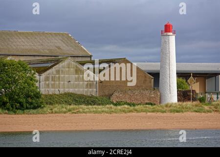 Le vieux phare arrière Montrose, à côté de la plage et à côté de quelques vieux entrepôts avec des côtés et des toits galvanisés, et un mur de pierre ancien. Banque D'Images