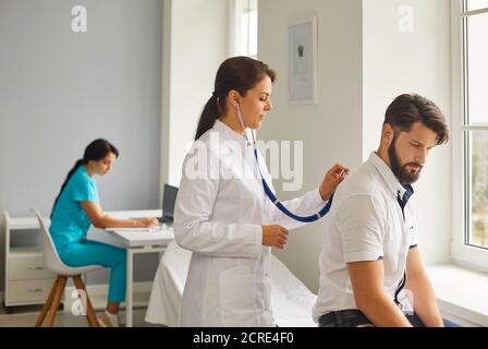 Une femme médecin écoute la respiration avec un stéthoscope chez un jeune patient de l'hôpital. Banque D'Images