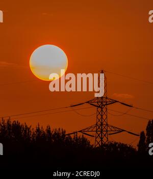 Wimbledon, Londres, Royaume-Uni. 20 septembre 2020. Lever de soleil orange coloré derrière un pylône électrique et des arbres dans le sud-ouest de Londres. Crédit : Malcolm Park/Alay Live News. Banque D'Images