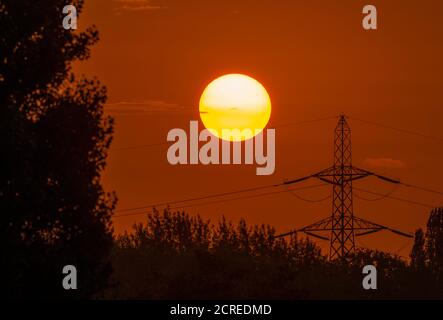 Wimbledon, Londres, Royaume-Uni. 20 septembre 2020. Lever de soleil orange coloré derrière un pylône électrique et des arbres dans le sud-ouest de Londres. Crédit : Malcolm Park/Alay Live News. Banque D'Images