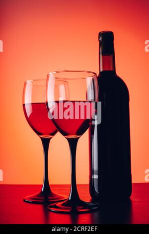 Verres à vin et bouteille sur fond rouge Banque D'Images