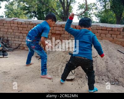 DISTRICT DE BILASPUR, INDE - 25 FÉVRIER 2020 : deux petits enfants indiens jouant ensemble sur le terrain de sol en fond de ciel. Banque D'Images