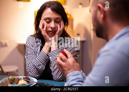 Femme qui a l'air choquée pendant la proposition de mariage tout en dînant. Romantique bonne femme caucasienne souriant sans voix, excitée, souriante, fiancée, romance. Banque D'Images