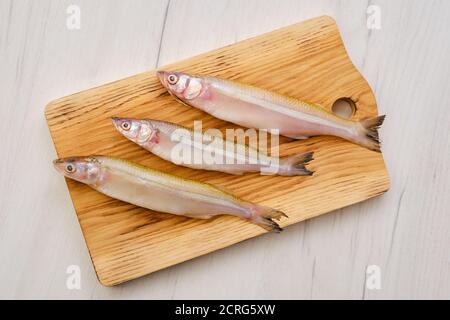 Vue de dessus de poisson frais cru éperlan sur la coupe de bois carte Banque D'Images