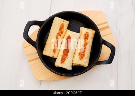 Vue de dessus de fines crêpes farcies à la viande de dinde dedans poêle à frire en fonte Banque D'Images