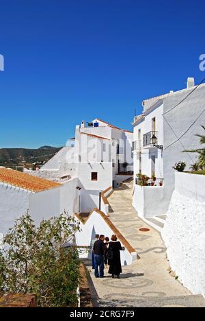 Touristes marchant le long de la rue dans le village blanc, Frigiliana, Espagne. Banque D'Images