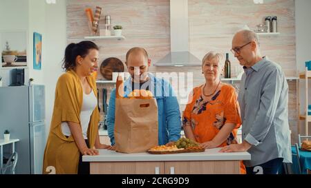 Portrait vidéo de la famille étendue heureuse souriant à l'appareil photo, assis dans la cuisine. Les gens dans la salle à manger autour du sac de papier avec des provisions regardant la web CAM Banque D'Images