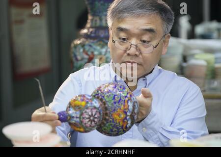 (200920) -- BEIJING, 20 septembre 2020 (Xinhua) -- Zhong Liansheng ajoute du glaçage au corps de cloisonne à l'usine d'émail de Beijing, capitale de la Chine, le 15 septembre 2020. En Chine, 'Jingtaran' représente un cloisonné spécial en cuivre et en porcelaine. Introduite dans les pays arabes pendant la dynastie Yuan (1271-1368) et devenant populaire pendant les années 'Jingtai' de la dynastie Ming (1368-1644), la cloisonne de Jingtaran utilise le cuivre rouge comme corps, avec des motifs structurés avec des fils de cuivre et peints avec du vernis émaillé. La fabrication doit passer par des dizaines de procédures includi Banque D'Images