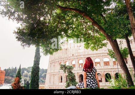 Rome, Italie - UNE jeune femme brésilienne adulte à tête rouge dans ses 20 ans regardant dans le Colisée pris dans un parc pendant l'après-midi. Banque D'Images