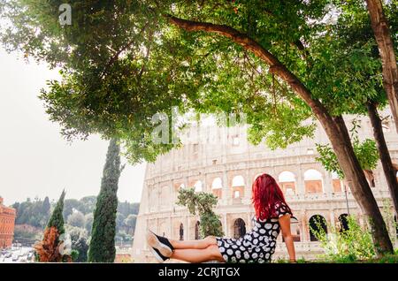 Rome, Italie - UNE jeune femme brésilienne adulte à tête rouge dans ses 20 ans regardant dans le Colisée pris dans un parc pendant l'après-midi. Banque D'Images