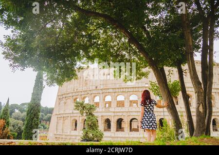 Rome, Italie - UNE jeune femme brésilienne adulte à tête rouge dans ses années 20s debout et regardant dans le Colisée pris dans un parc pendant l'après-midi. Banque D'Images