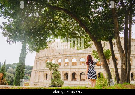 Rome, Italie - UNE jeune femme brésilienne adulte à tête rouge dans ses années 20s debout et regardant dans le Colisée pris dans un parc pendant l'après-midi. Banque D'Images